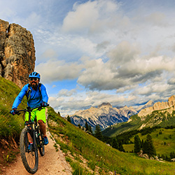 View of cyclist riding mountain bike on single trail in Dolomites, Cinque Torri, South Tirol, Italy