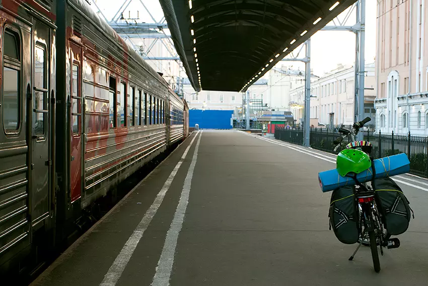 A bicycle with tourist equipment on the station feather. The train is preparing to leave. Tourist and solo travel concept. Road trip, staycations and back to basics idea.